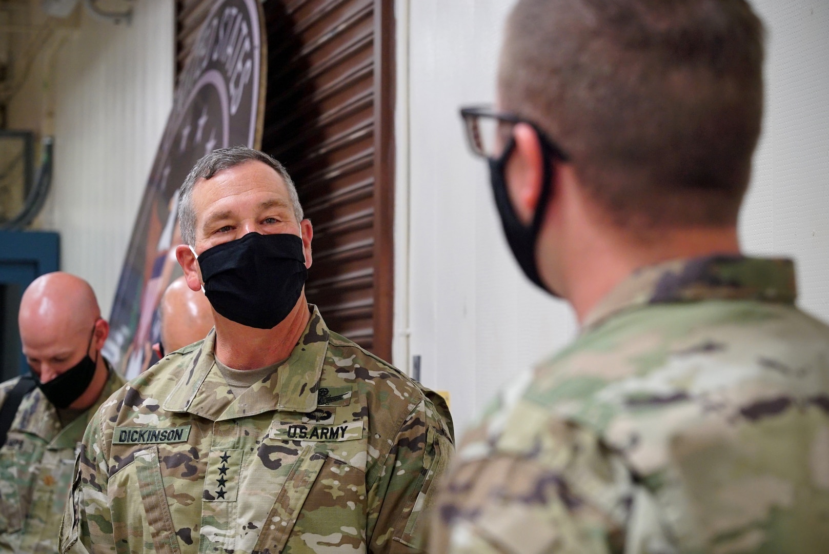 Two men in military uniform stand across from each other, talking.