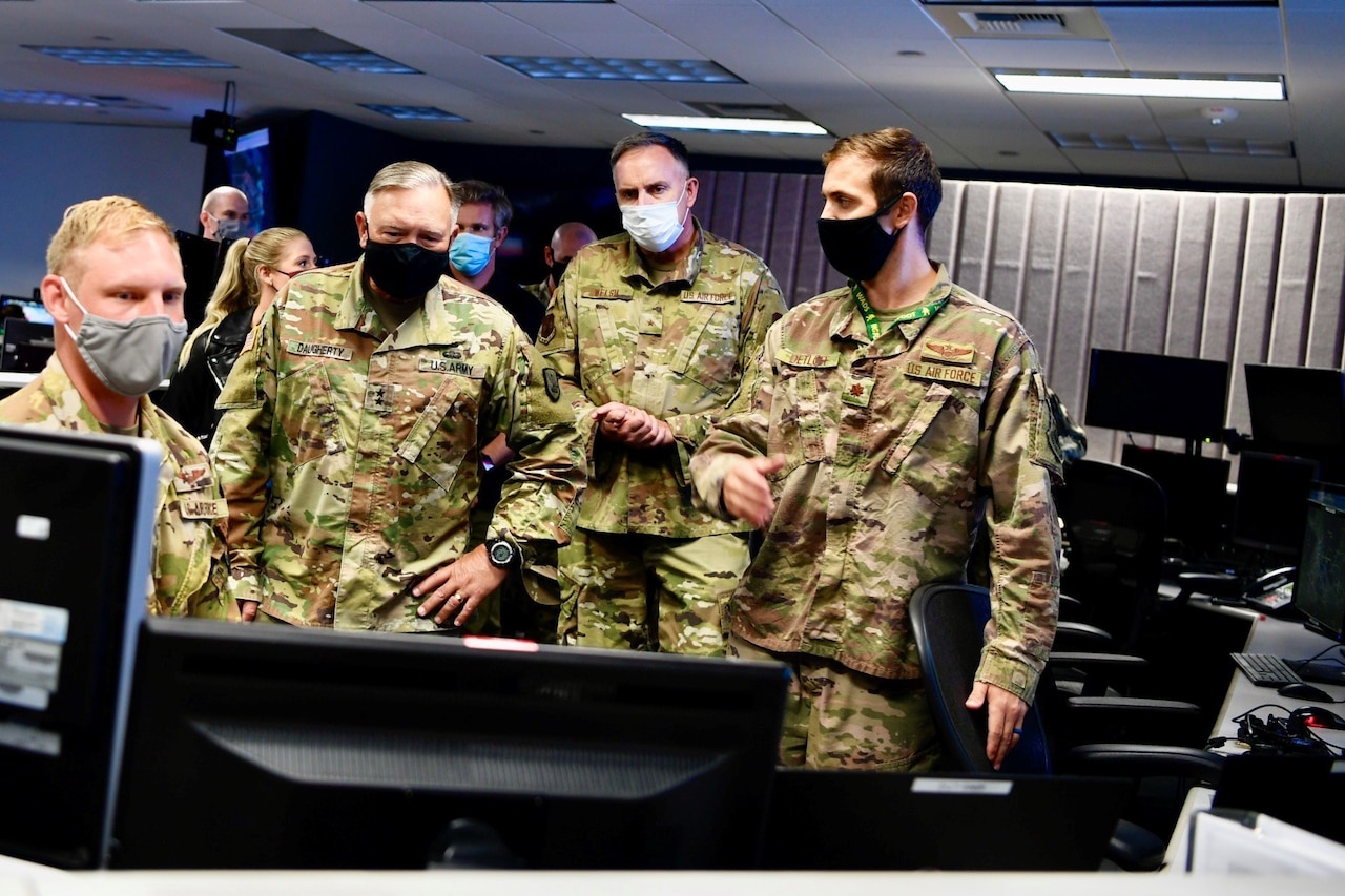 Four men in uniform observe a computer screen.