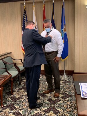 Defense Logistics Agency Disposition Services Director Mike Cannon, left, presents Greg Dangremond with a Superior Civilian Service Award for Dangremond’s four months as a liaison at the Agency Synchronization Operations Center at DLA headquarters on Fort Belvoir, Virginia.