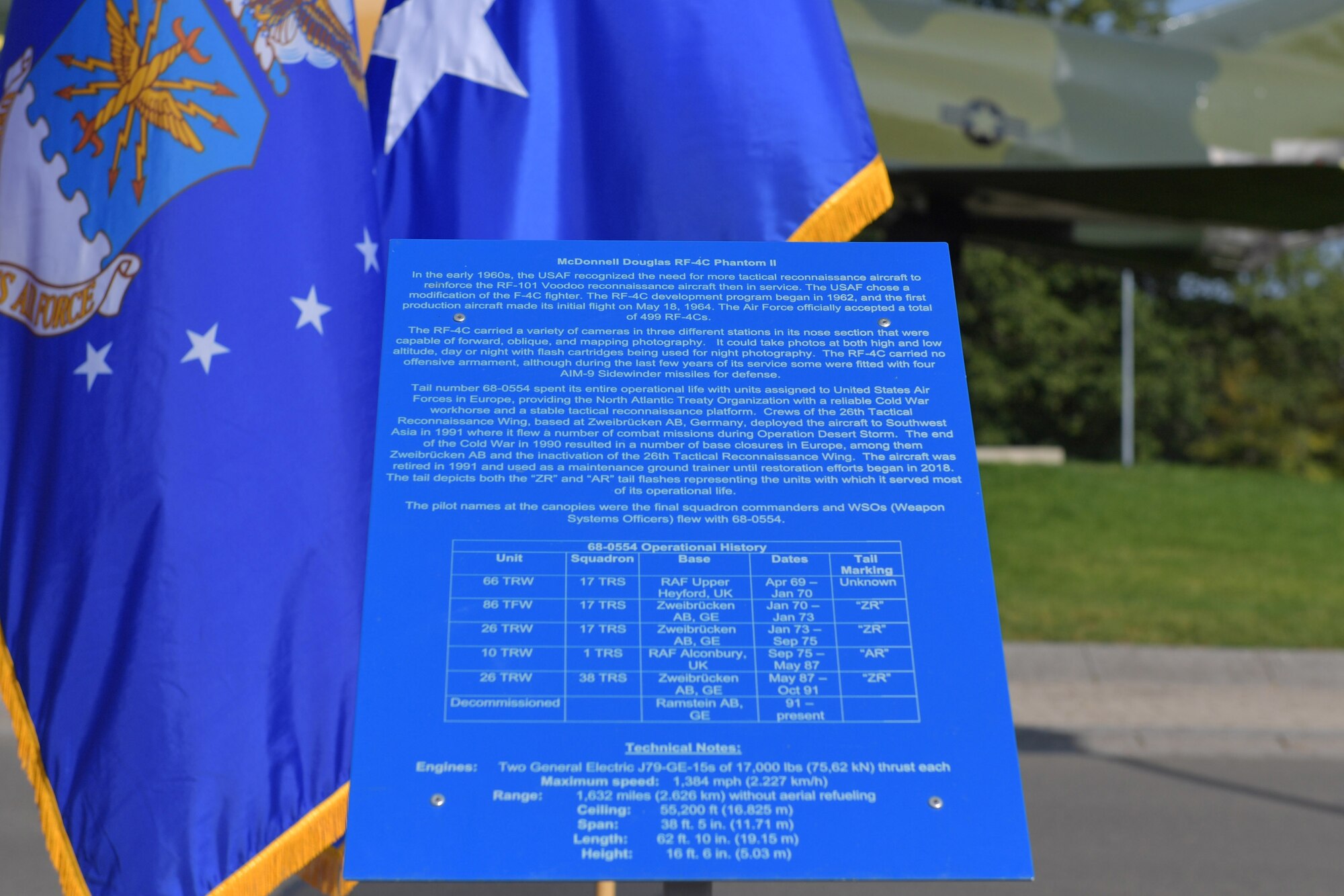 A historical information plate stands in front of an aircraft static display.