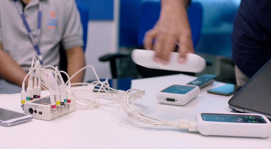 Researchers work with a monitor that has many wires extending from it.