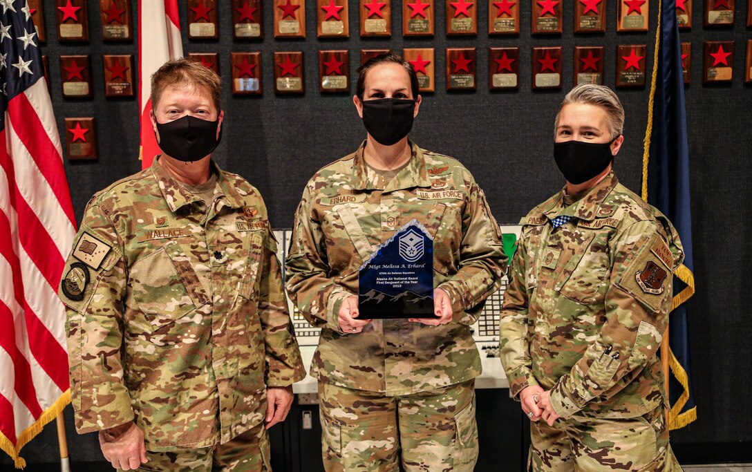 Alaska Air National Guardsmen Lt. Col. Shane Wallace and Chief Master Sgt. Heather Pineiro, the Commander and Chief Enlisted Manager assigned to the 176th Air Defense Squadron stand beside 1st Sgt. Melissa Erhard, the Alaska Air National Guard's 2019 First Sergeant of the Year, Sept. 15, 2020 on Joint Base Elmendorf-Richardson. Erhard distinguished herself in 2019 through her ability to foster resiliency among her Airmen and her community. The red stars in the backdrop represent the number of Russian intercepts made by the unit through the years, whose mission is to defend the nation's Air Sovereignty in the region. (U.S. Army National Guard photo by Sgt. Seth LaCount/Released)