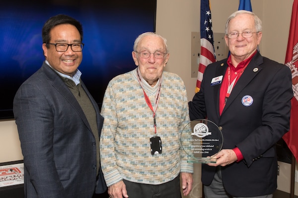 Wendell “Buddy” Barnes (far right), national president of the Society of American Military Engineers (SAME), presents Bud Ossey (center) with a placard recognizing his 73 years of membership with SAME during a Portland District, U.S. Army Corps of Engineers historical celebration at the district’s headquarters in downtown Portland in November 2019. Also pictured is Terry Hosaka, the SAME Portland Post president.