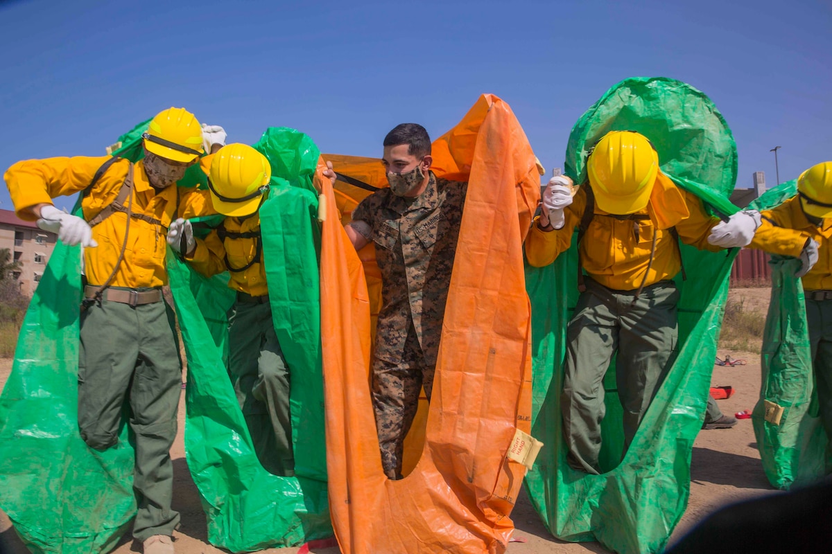 A Marine helps service members put on protective coverings.