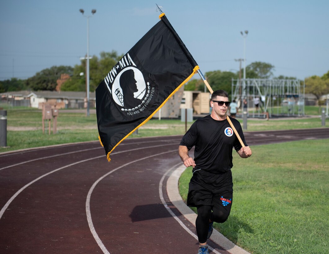 Tech. Sgt. Christopher Johnson, Honor Guard NCO in charge, runs around the track while carrying the prisoner of war and missing in action flag on Sept. 17, 2020 at Laughlin Air Force Base, Texas. Johnson ran the track while proudly carrying the flag to show his respect and raise awareness of POW/MIA military members.