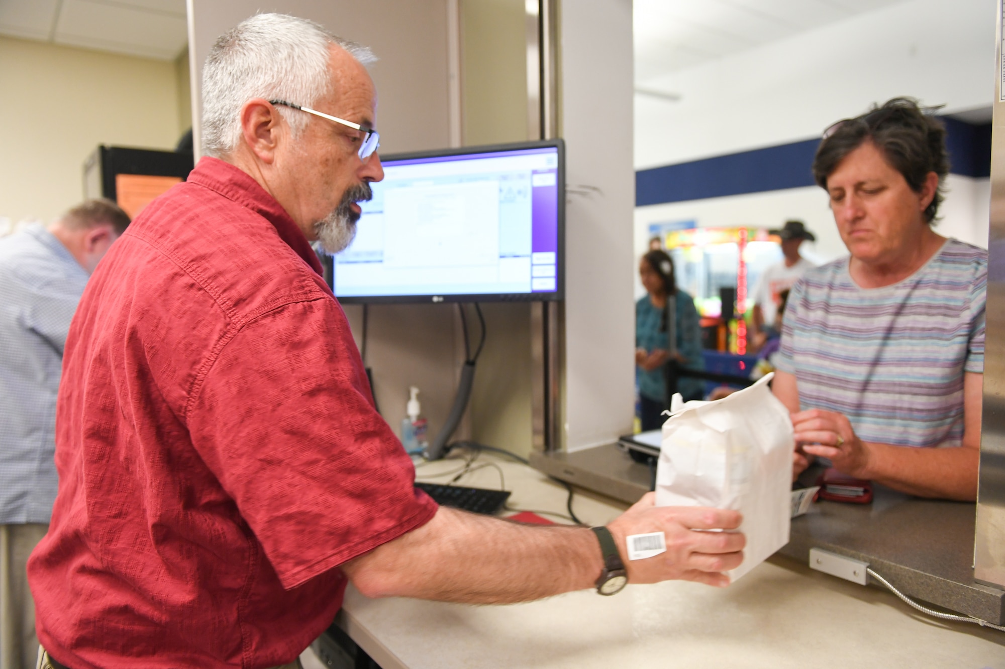Pharmacy technician Andy Pollaehne hands a prescription to Cary Fisher at the Satellite Pharmacy located inside the AAFES Base Exchange at Hill Air Force Base. Beginning Nov. 2, the Satellite Pharmacy windows will reopen.