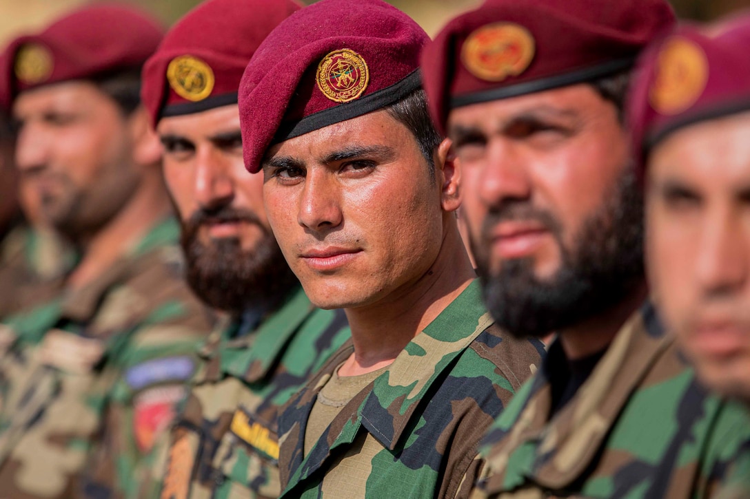 Multiple soldiers stand in formation.  Each wears a maroon beret.