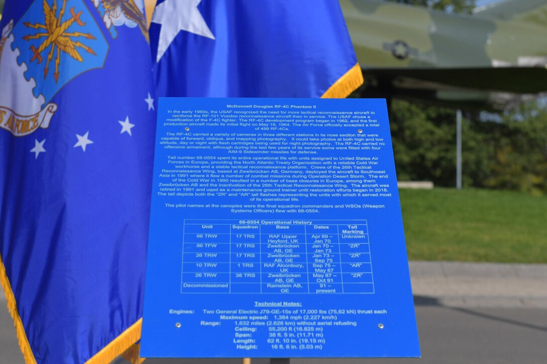 A historical information plate stands in front of an aircraft static display.