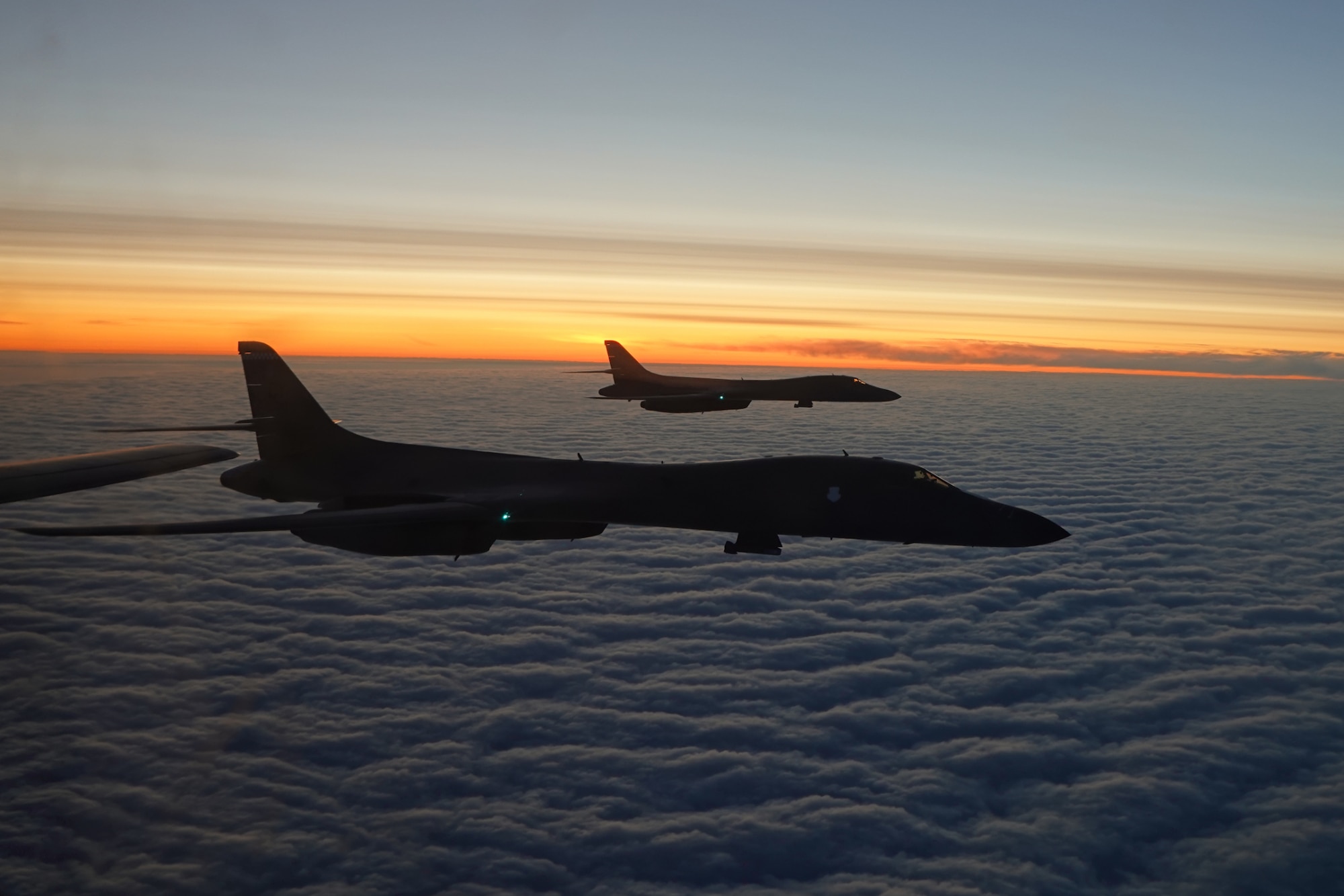 Photo of two B-1's flying over clouds