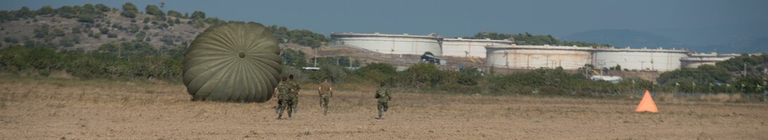 Hellenic forces members run to recover a parachute.