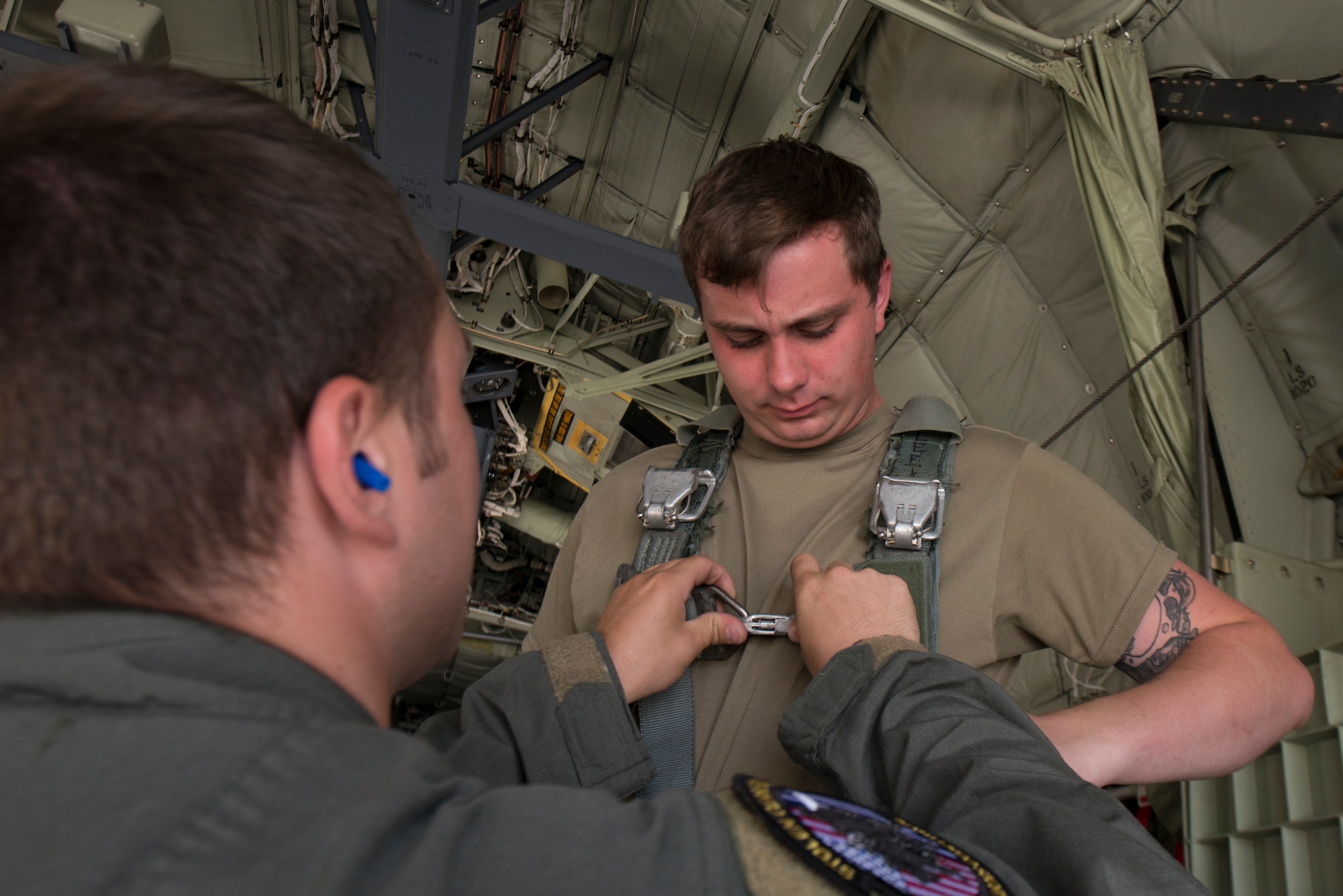 A loadmaster secures a harness on an Airman.