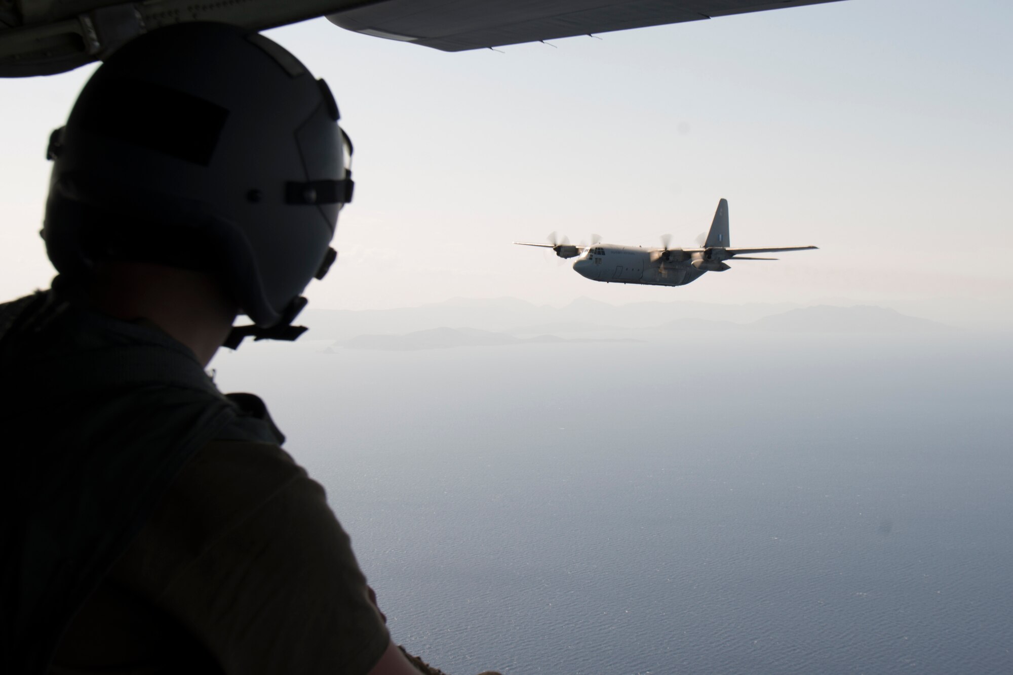 An Airman watches a C-130J fly overhead.