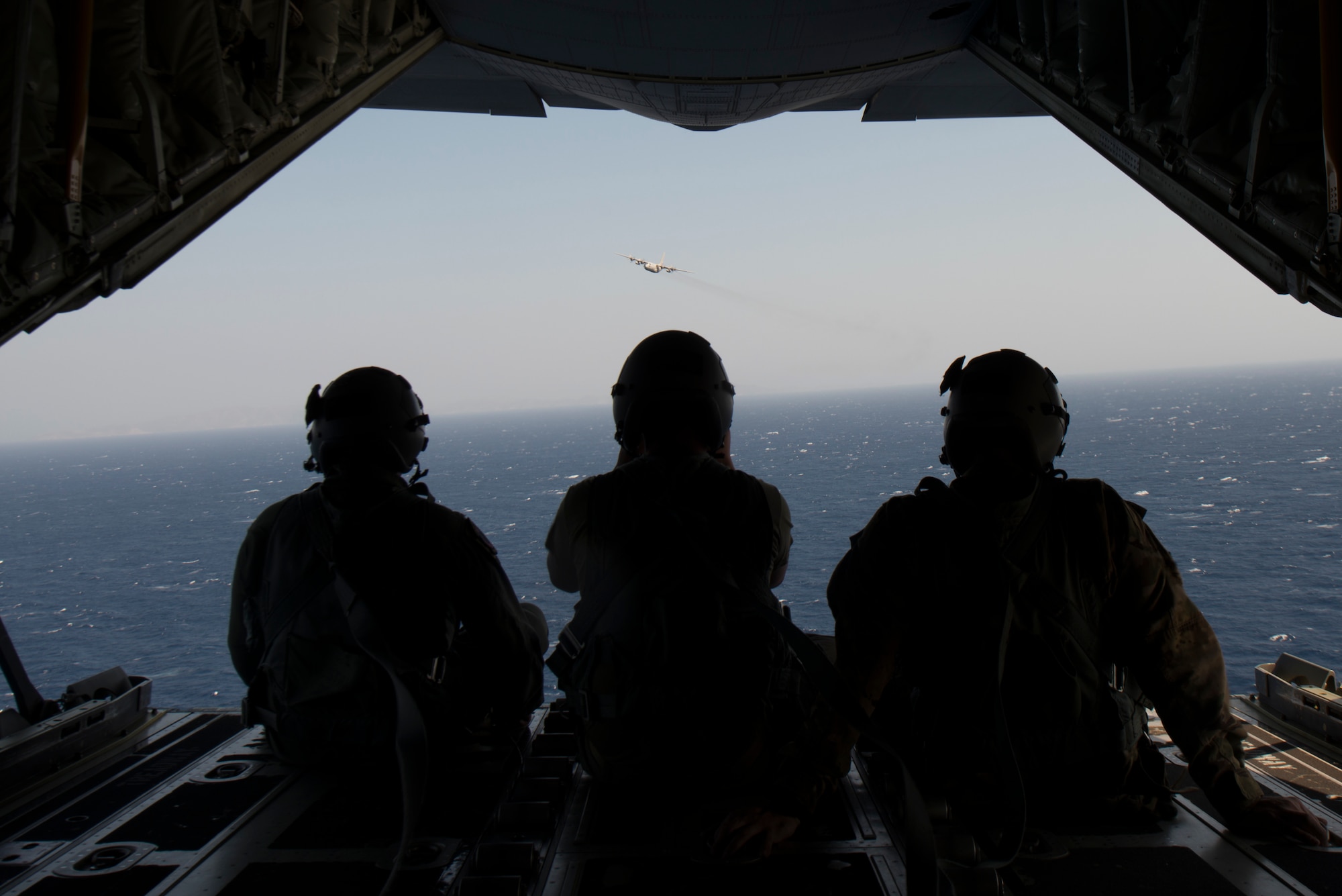 Airmen watch a plane fly over while on a plane.