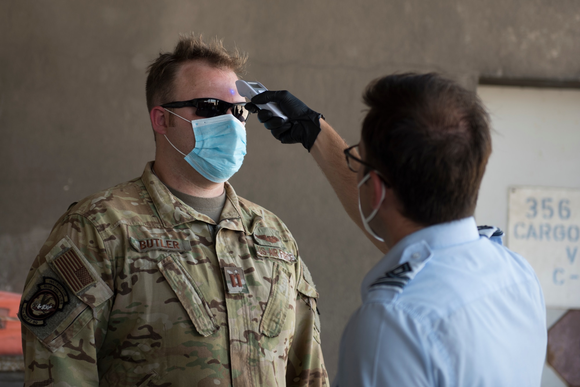 A Greek national checks a pilot's temperature.