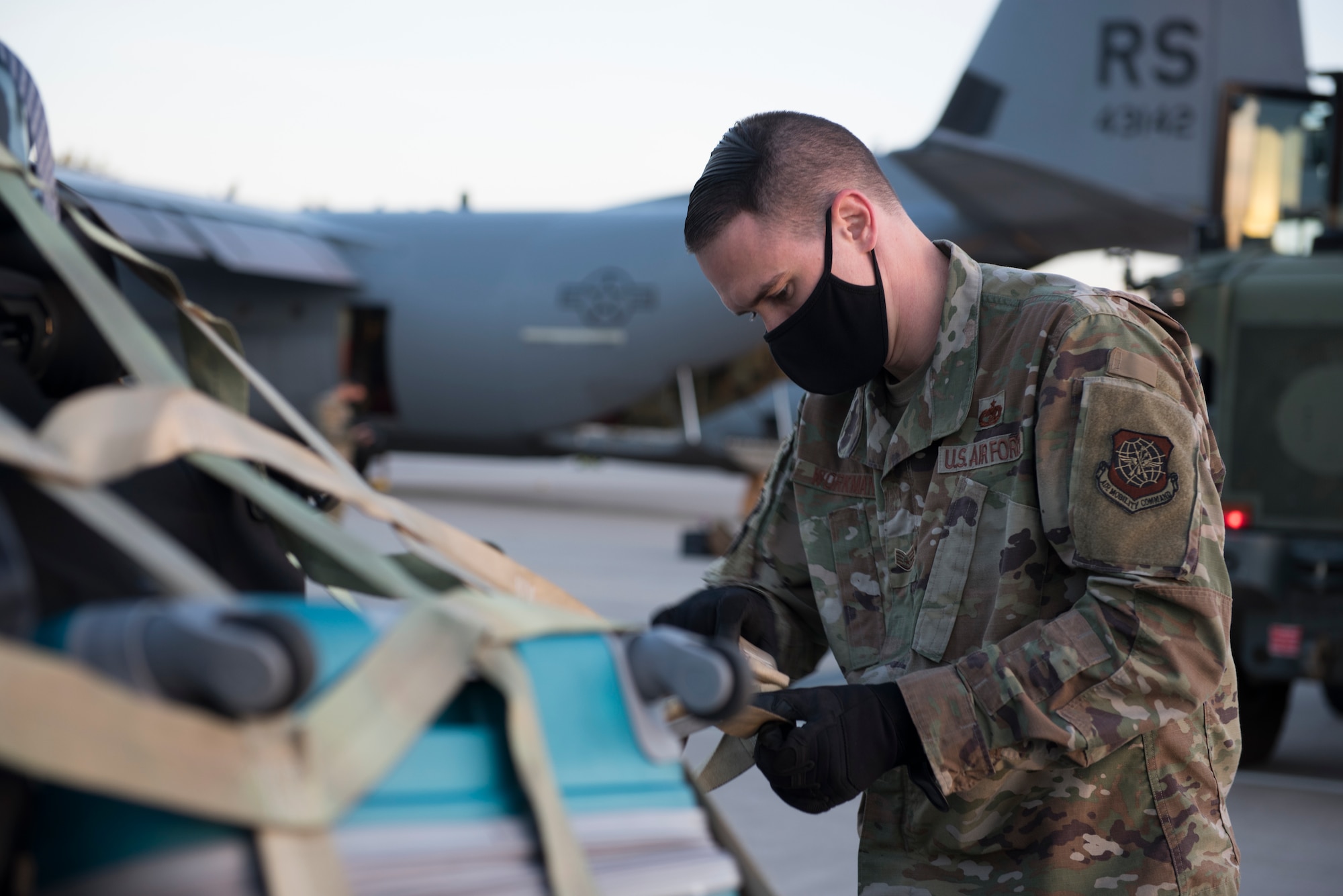 An Airman fastens luggage to a pallet