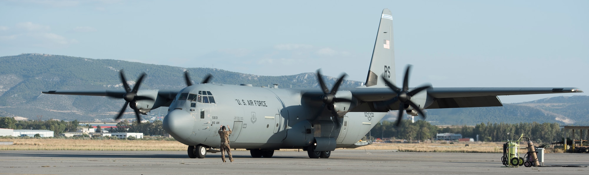 An Airman assigned to the 86th Maintenance Squadron marshals a C-130J aircraft.