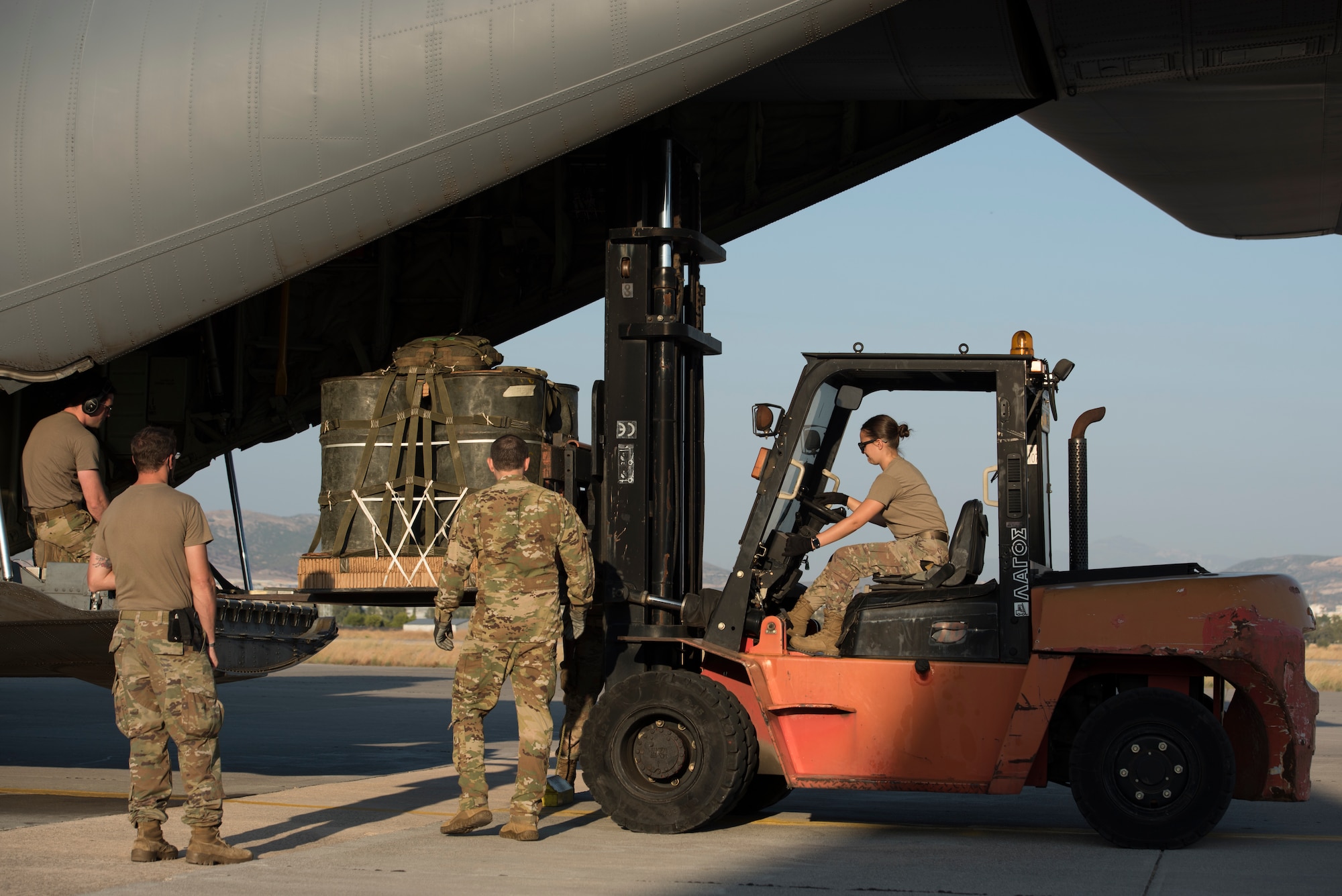An Airman uses a forklift to place an airdrop on an aircraft.