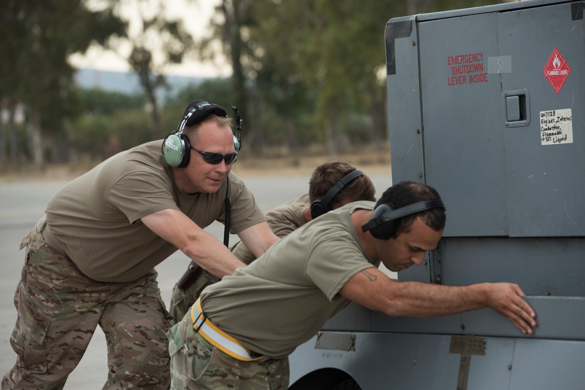 Airmen push a generator towards an aircraft.
