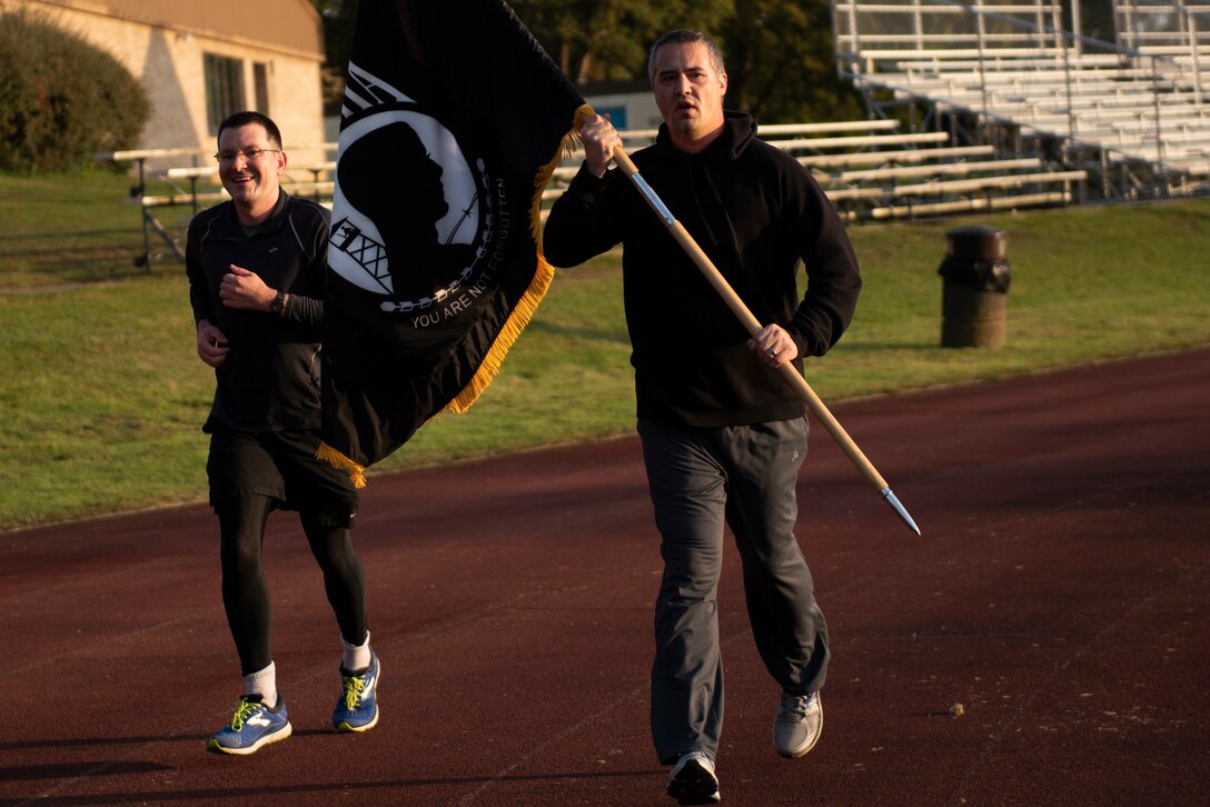 Volunteers from the 48th Fighter Wing run with the POW/MIA flag at Royal Air Force Lakenheath, England, Sept. 17, 2020. National POW/MIA Recognition Day is commemorated on the third Friday of every September to honor America's Prisoners of War and those who are Missing in Action from past conflicts. (U.S. Air Force photo by Airman 1st Class Jessi Monte)