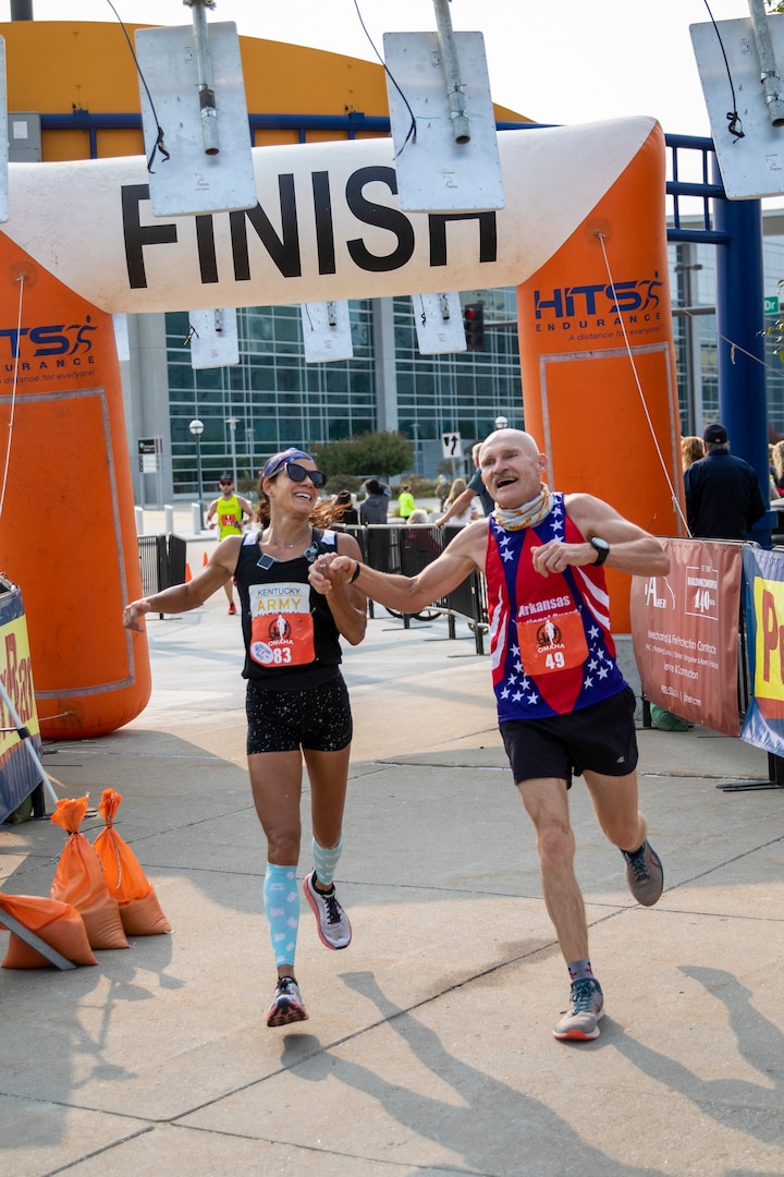 Lt. Col. Varinka Ensminger, left, Kentucky Army National Guard, holds hands with Master Sgt. James Bresette, Arkansas Army National Guard, as they finish the Omaha Marathon Sept. 20, 2020, in Omaha, Nebraska. This was long-time National Guard Marathon Team runner Bresette’s final marathon as a Guardsman, and Ensminger was the top National Guard female marathon runner for 2020.