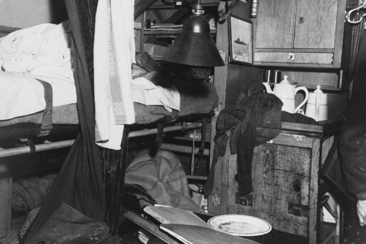 Items are strewn about a small room that includes a bunk and a few cabinets.
