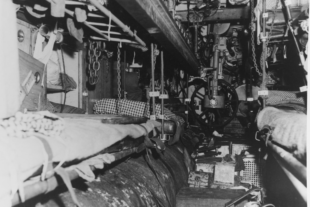 A cramped room includes large pipes, tubes and levers.