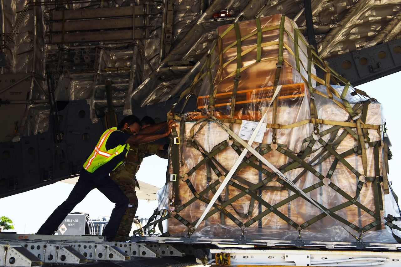 Ramp service technicians wearing face masks off-load a mobile field hospital.