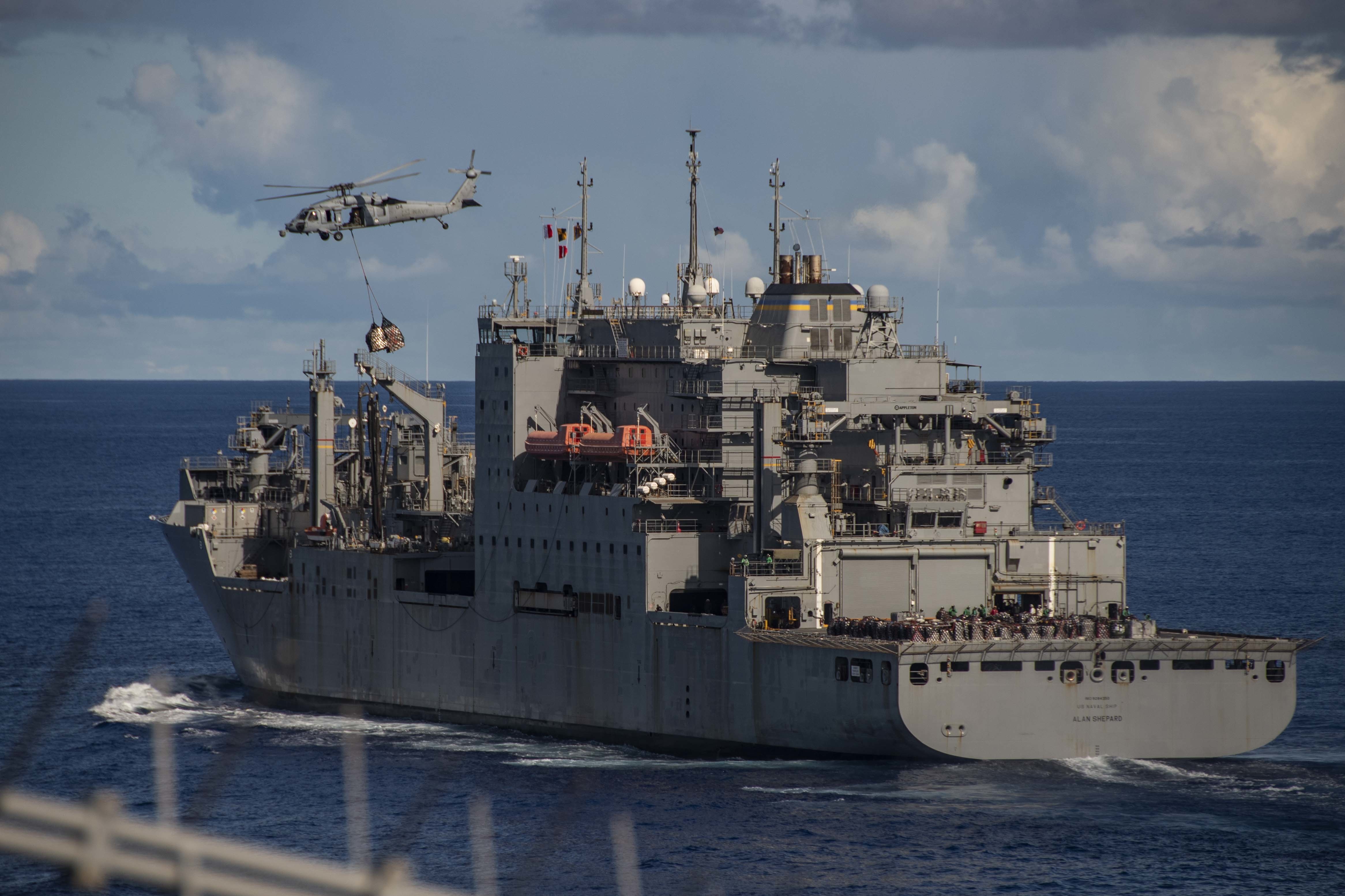 An MH-60S Sea Hawk, attached to the "Island Knights" of Helicopter Sea Combat Squadron (HSC) 25, transports supplies to the Navy's only forward-deployed aircraft carrier USS Ronald Reagan (CVN 76) during a replenishment-at-sea with dry cargo and ammunition ship USNS Alan Shepard (T-AKE 3) in support of Valiant Shield 2020.