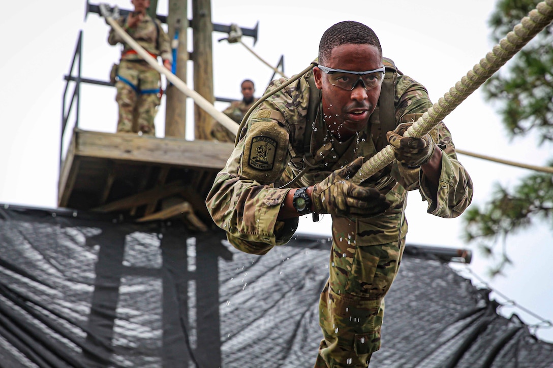 An Army ROTC' before 'cadet slides down a rope suspended in the air.