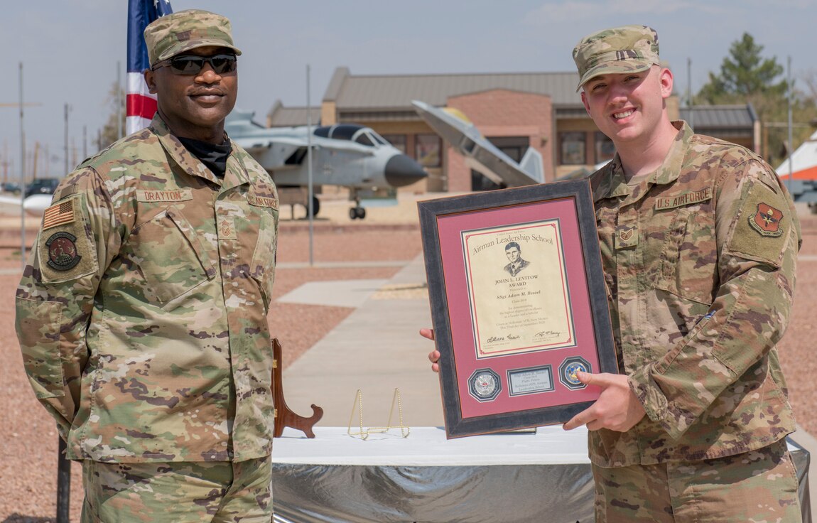 Staff Sgt. Adam Reszel, right, assigned to the 49th Equipment Maintenance, accepts the John L. Levitow award during the graduation of ALS class 20-6, Sept. 22, 2020, on Holloman Air Force Base, New Mexico. The Levitow award is presented to the student demonstrating the highest level of leadership and scholastic performance, and is partially determined by the assignment of points by their peers. (U.S. Air Force photo by Airman 1st Class Quion Lowe)