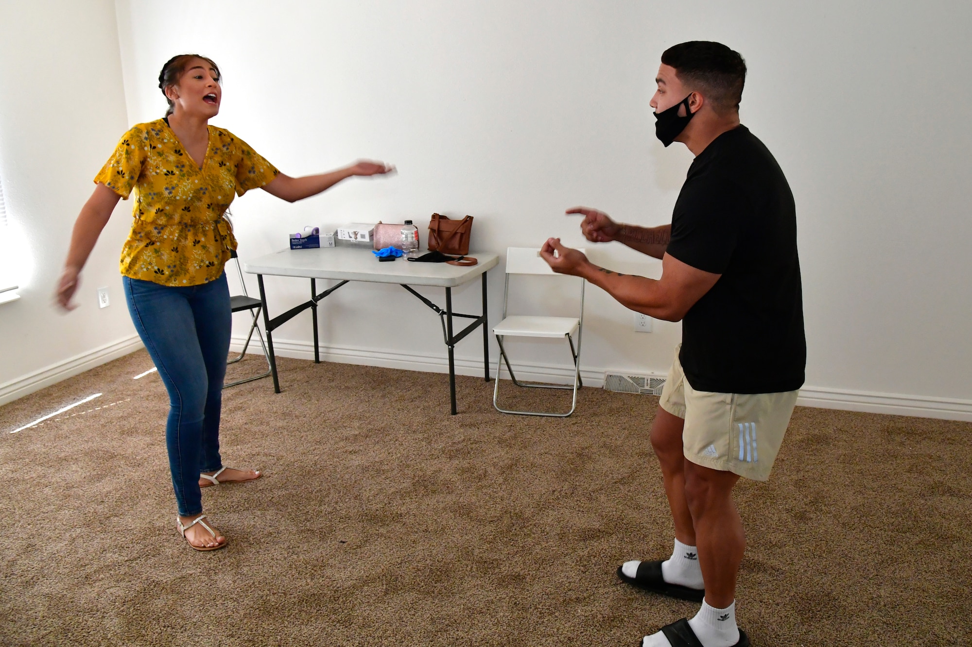 Airman Paola Castro (left), entry controller, and Senior Airman Braeden Lehman, patrolman, both with the 75th Security Forces Squadron, simulate a domestic dispute in an empty living room.