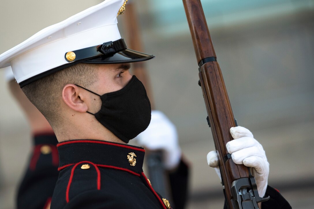 A service member wearing a mask holds a weapon.