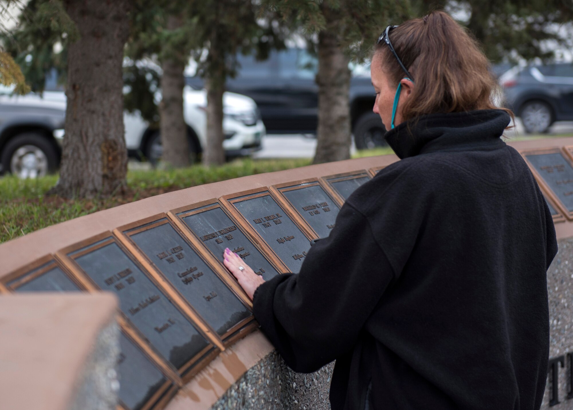 A surviving family member places her hand on the name plaque of one of the lost Yukla 27 crew members at the Yukla 27 25th anniversary memorial ceremony at Joint Base Elmendorf-Richardson, Alaska, Sept. 22, 2020. Yukla 27, a U.S. Air Force E-3 Sentry airborne warning and control system aircraft assigned to the 962nd AACS, encountered a flock of geese Sept. 22, 1995, and crashed shortly after takeoff on a routine surveillance training sortie, killing all 24 Canadian and U.S. Airmen aboard.