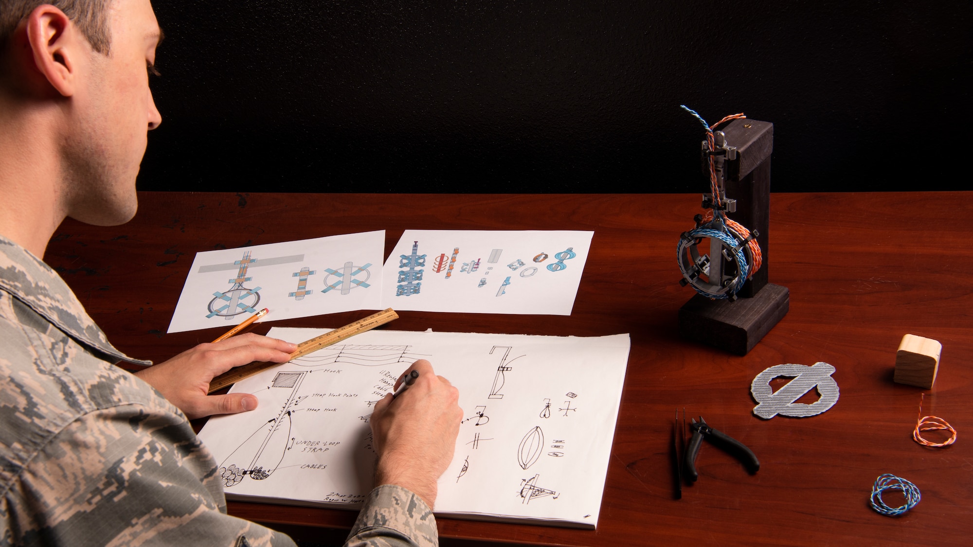 Senior Airman Hartman, 726th Air Command Squadron cyber transport technician, sketches an idea for his invention of a cable management system, Sept. 16, 2020, at Mountain Home Air Force Base, Idaho. Hartman started with sketches and moved to digital modeling and 3D printing as way to communicate the benefits and viability of his device to senior wing leadership. (U.S. Air Force photo by Senior Airman Andrew Kobialka)