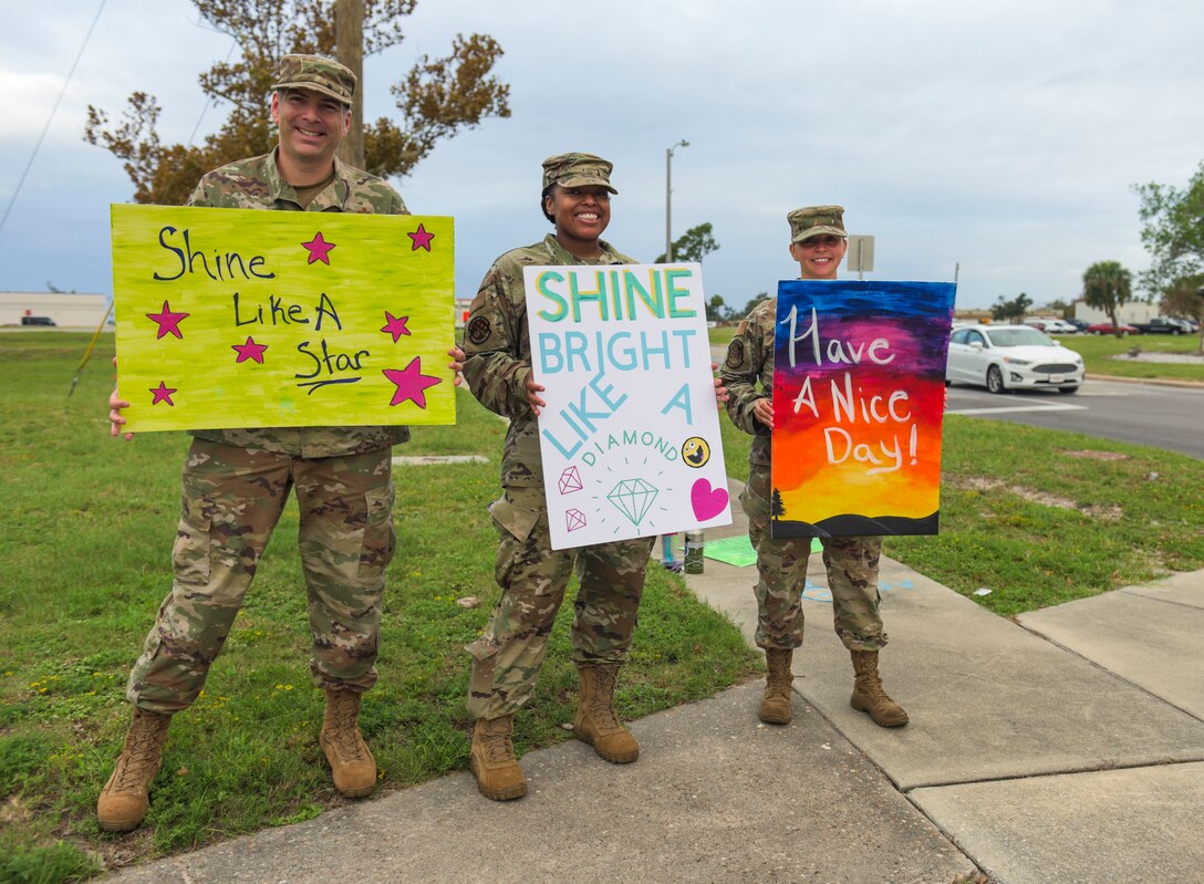 U.S. Air Force Master Sgts. James Fisher with the 325th Civil Engineer Squadron, superintendent, left, Charlene Rockett with the 325th Communications Squadron, first sergeant, center, and Moriah Washburn with the 325th Contracting Squadron and 325th CE, first sergeant, right, wave handmade signs near the inbound lane at Tyndall Air Force Base, Florida, Sept. 24, 2020. Tyndall's first sergeants converged near the base's entry gates to wave morale and resiliency signs at passersby. (U.S. Air Force photo by Staff Sgt. Magen M. Reeves)