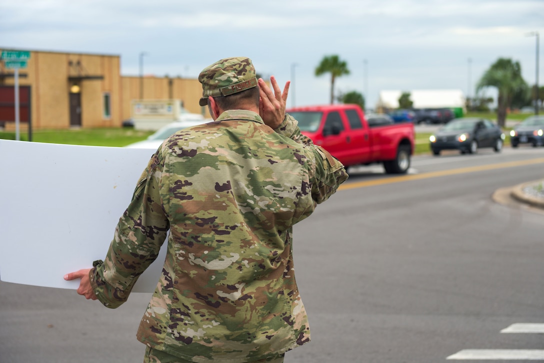 U.S. Air Force Master Sgt. James Fisher with the 325th Civil Engineer Squadron, superintendent, waves a handmade sign near the inbound lane at Tyndall Air Force Base, Florida, Sept. 24, 2020. Fisher was part of a group effort fronted by Tyndall’s first sergeants to pump up morale on base. (U.S. Air Force photo by Staff Sgt. Magen M. Reeves)