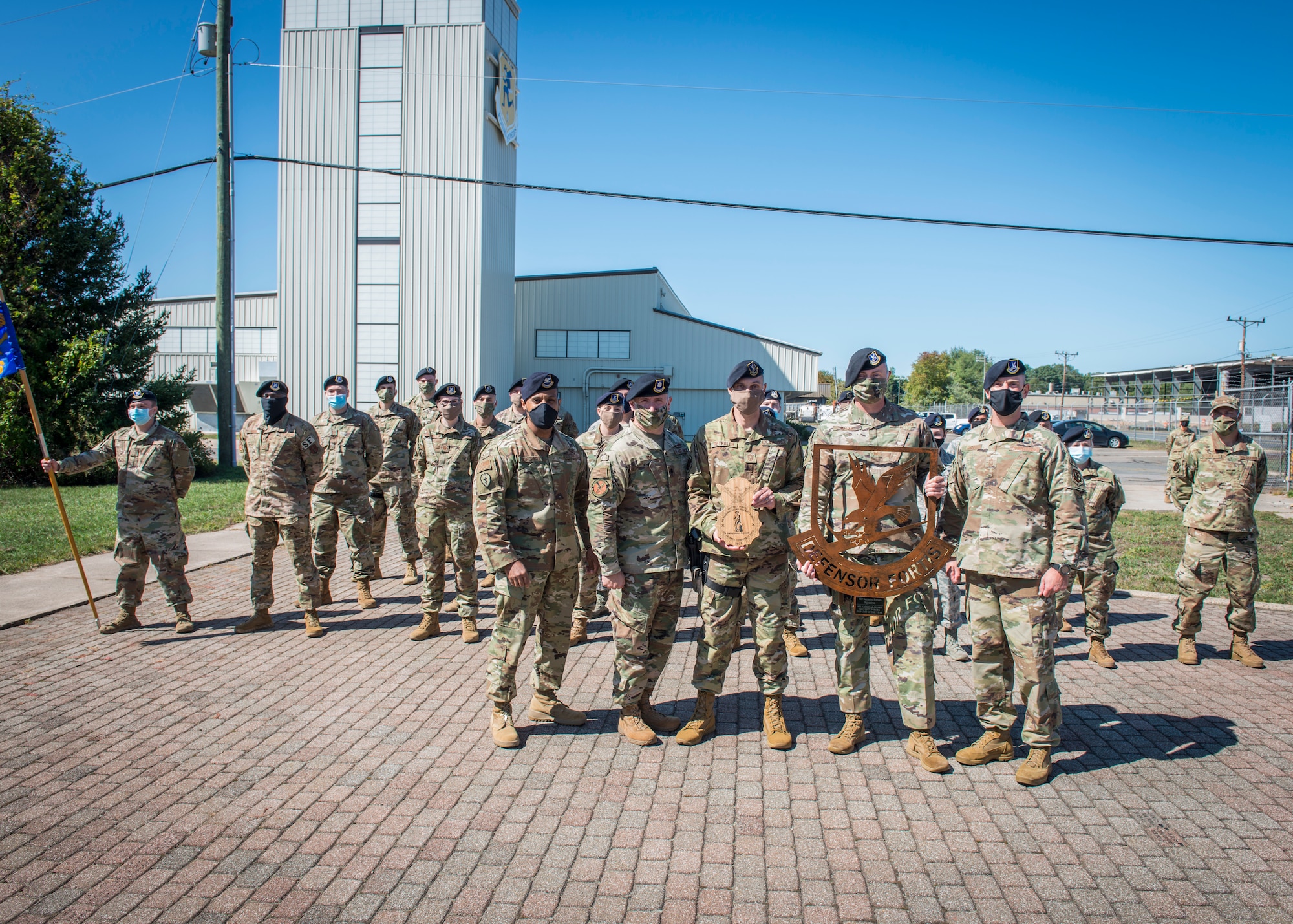 (Front, left to right) Col. Victor Moncrieffe, Air National Guard Chief of Security Forces, Lt. Col William Deme, 103rd Security Forces Squadron commander, Senior Master Sgt. James Reynolds, 103rd Security Forces Squadron Defender, Senior Master Sgt. Richard Marks, 103rd Security Forces Squadron Security Forces manager, and Chief Master Sgt. T.J. Hall, Air National Guard Security Forces career field manager, pose for a photograph with a formation of 103rd Security Forces Squadron Defenders following an award ceremony at Bradley Air National Guard Base, East Granby, Connecticut, Sept. 19, 2020. The squadron received the award for 2019 Air National Guard Outstanding Security Forces Unit of the Year, and Reynolds was named 2019 Security Forces Air Reserve Component Senior Noncommissioned Officer of the Year. (U.S. Air National Guard photo by Staff Sgt. Steven Tucker)