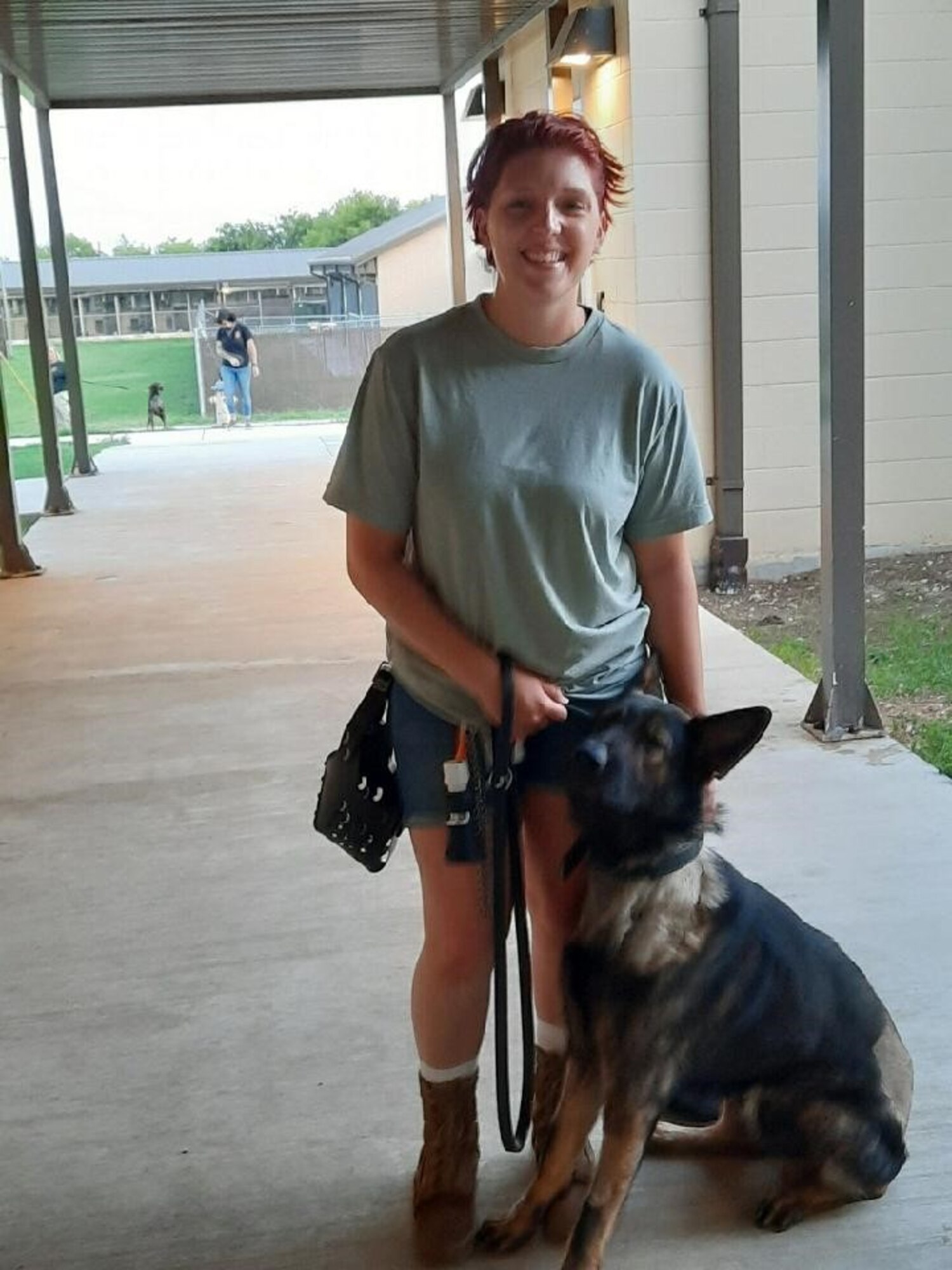 Photo of Airman with German Shepard military working dog by her side.