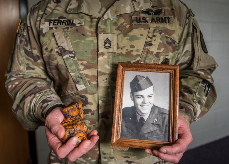 U.S. Army Sgt. 1st Class Corrie Ferrin, 1-210th Aviation Regiment senior instructor, holds mementos of his adopted grandfather—a portrait in his left hand and a paperweight in his right—on Sept. 18, 2020 at Joint-Base Langley Eustis, Virginia. Ferrin learned to value family—whether or not they are related by blood—from his grandfather, who raised Ferrin after his mother left him and his father was busy working to support the family. (U.S. Air Force photo by Staff Sgt. Joshua Magbanua)