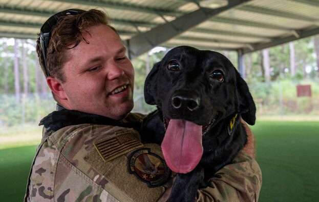 An Airman holds a dog.