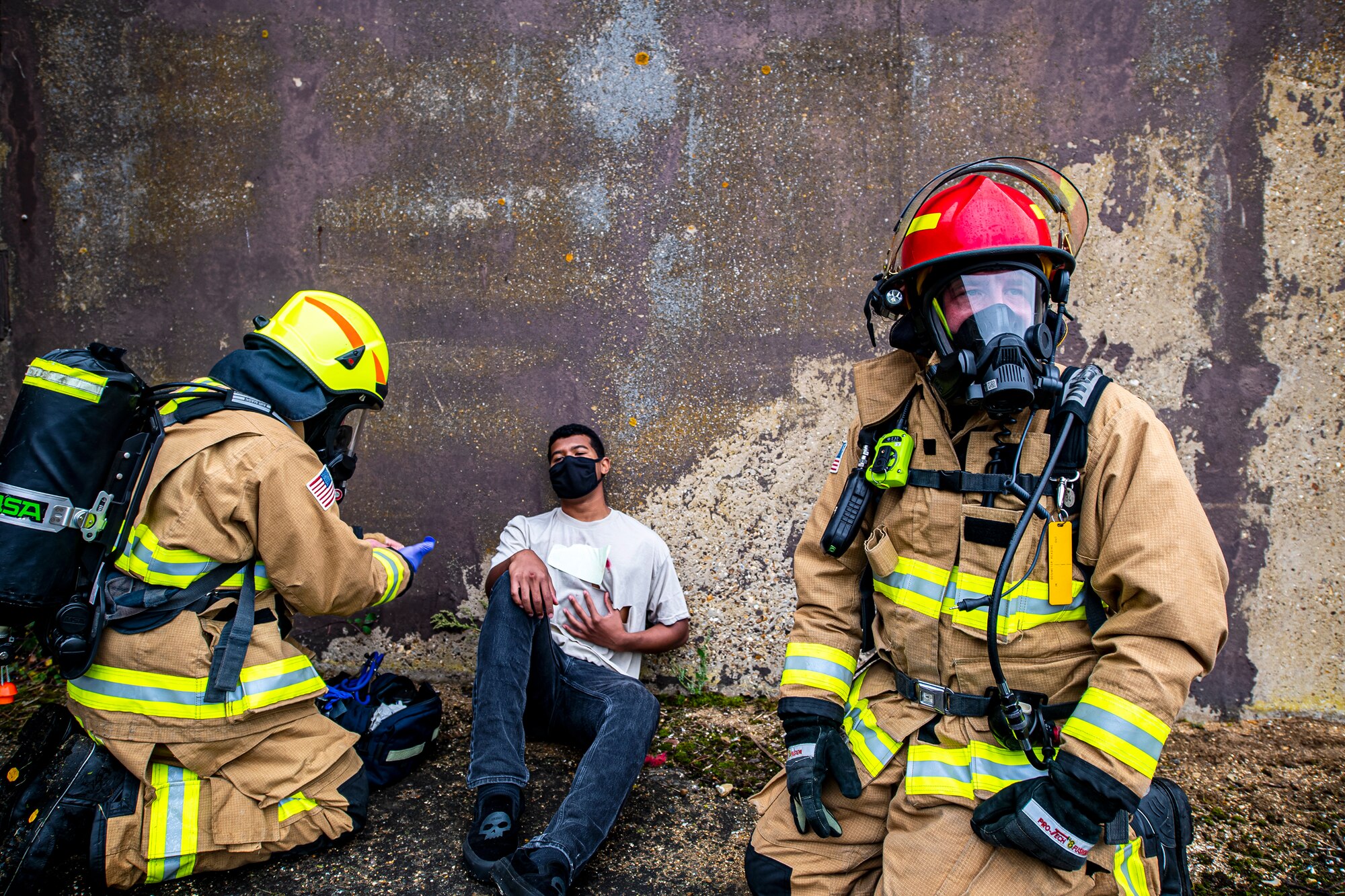 Firefighters from the 423rd Civil Engineer Squadron, tend to Airman 1st Class Rashawn Carter, center, 423rd Communications Squadron cyber transport systems technician and simulated victim, during an exercise at RAF Molesworth, England, Sept. 23, 2020. The exercise tested Airmen and firefighter’s preparedness and interoperability by responding to a simulated drone ordinance attack. (U.S. Air Force photo by Senior Airman Eugene Oliver)