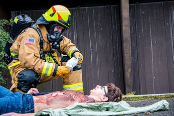 A firefighter from the 423rd Civil Engineer Squadron, top, tends to Wyatt Evett, simulated victim, during an exercise at RAF Molesworth England, Sept. 23, 2020. The exercise tested Airmen and firefighter’s preparedness and interoperability by responding to a simulated drone ordinance attack. (U.S. Air Force photo by Senior Airman Eugene Oliver)