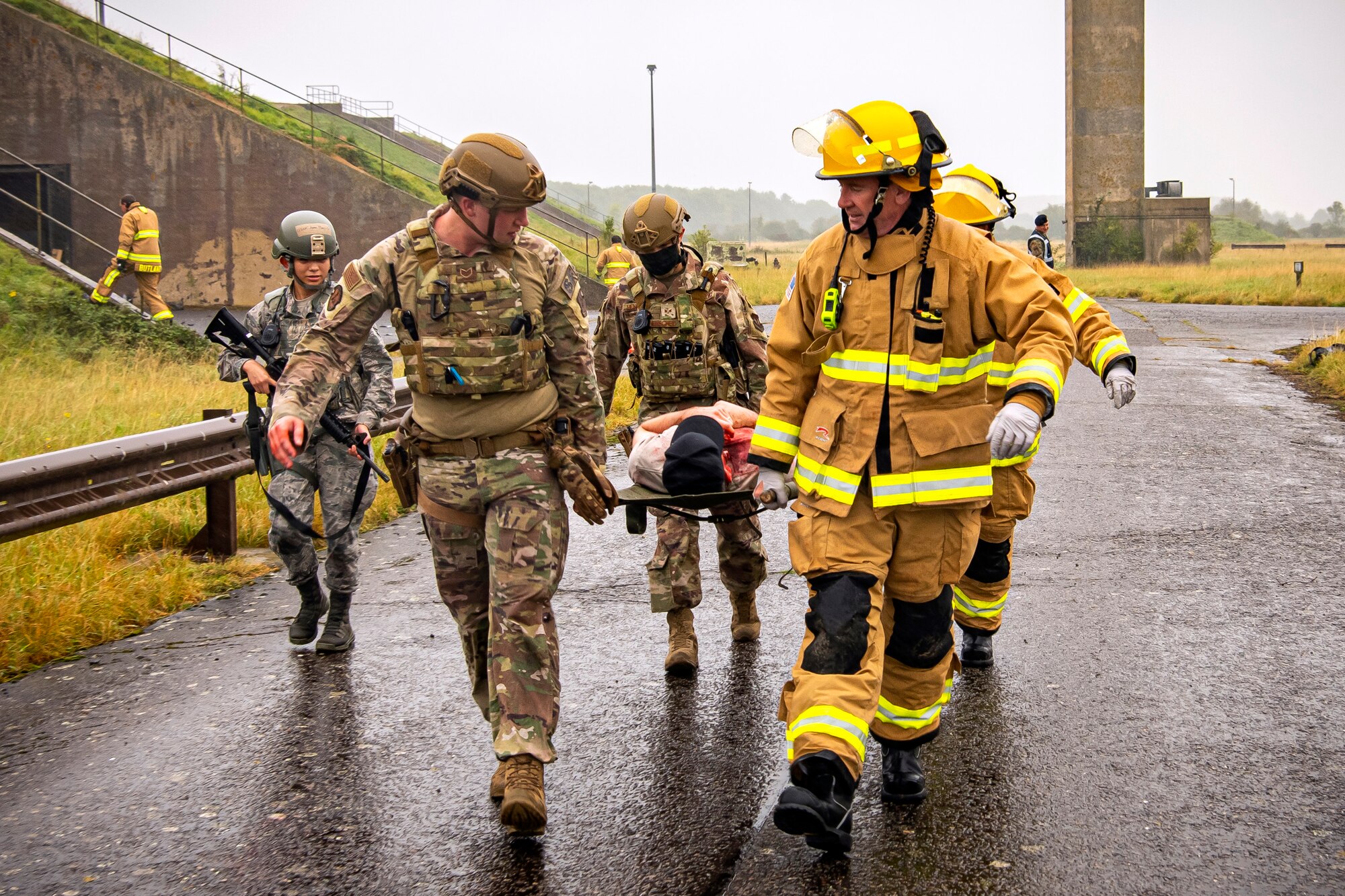 Airmen and firefighters from the 501st Combat Support Wing, carry a simulated victim in a stretcher during an exercise at RAF Molesworth, England, Sept. 23, 2020. The exercise tested Airmen and firefighter’s preparedness and interoperability by responding to a simulated drone ordinance attack. (U.S. Air Force photo by Senior Airman Eugene Oliver)