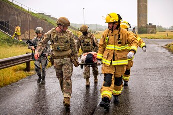 Airmen and firefighters from the 501st Combat Support Wing, carry a simulated victim in a stretcher during an exercise at RAF Molesworth, England, Sept. 23, 2020. The exercise tested Airmen and firefighter’s preparedness and interoperability by responding to a simulated drone ordinance attack. (U.S. Air Force photo by Senior Airman Eugene Oliver)