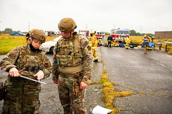 U.S. Air Force Tech. Sgt. Chelsea Reynolds, left, 423rd Security Forces Squadron flight sergeant, discusses the crime scene with Staff Sgt. Scott Marvin, right, 423rd SFS systems flight sergeant, during an exercise at RAF Molesworth, England, Sept. 23, 2020. The exercise tested Airmen and firefighter’s preparedness and interoperability by responding to a simulated drone ordinance attack. (U.S. Air Force photo by Senior Airman Eugene Oliver)