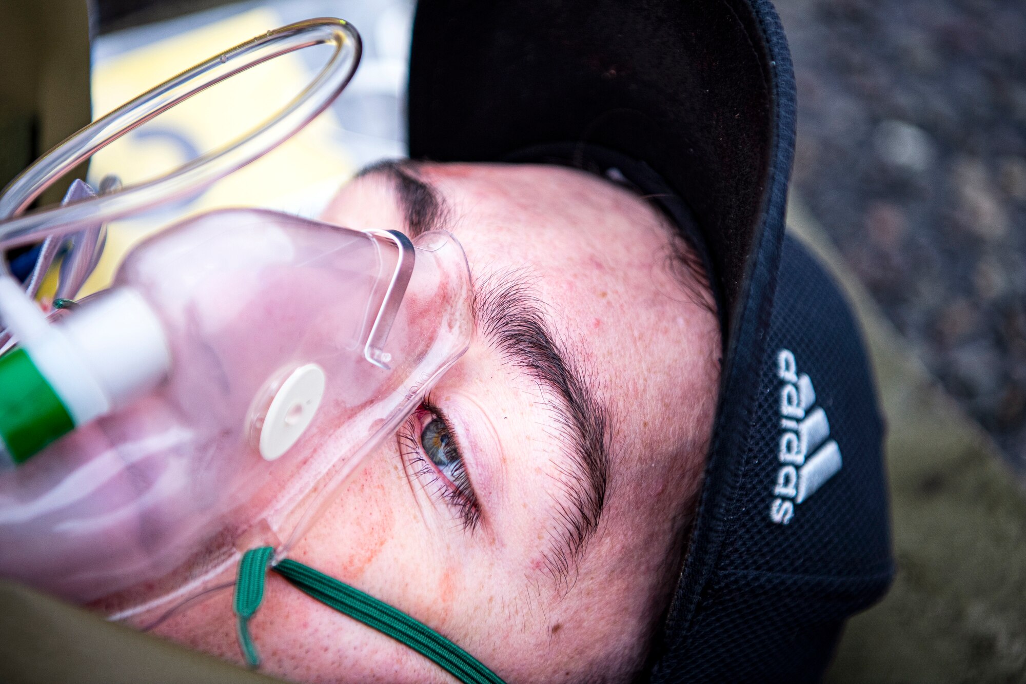 U.S. Air Force Senior Airman Kenneth Jones, 423d Communications Squadron transmission systems technician and simulated victim, breathes from an oxygen mask during an exercise at RAF Molesworth, England, Sept. 23, 2020.The exercise tested Airmen and firefighter’s preparedness and interoperability by responding to a simulated drone ordinance attack. (U.S. Air Force photo by Senior Airman Eugene Oliver)