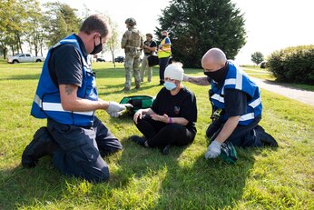 422nd Civil Engineer firefighters assist Angie Wells, 422nd Air Base Squadron accounting and simulated victim, during an exercise at RAF Croughton, England, Sept. 22, 2020. The 501st Combat Support Wing exercise tested preparedness and interoperability by responding to a simulated active stabber situation. (U.S. Air Force photo by Senior Airman Jennifer Zima)