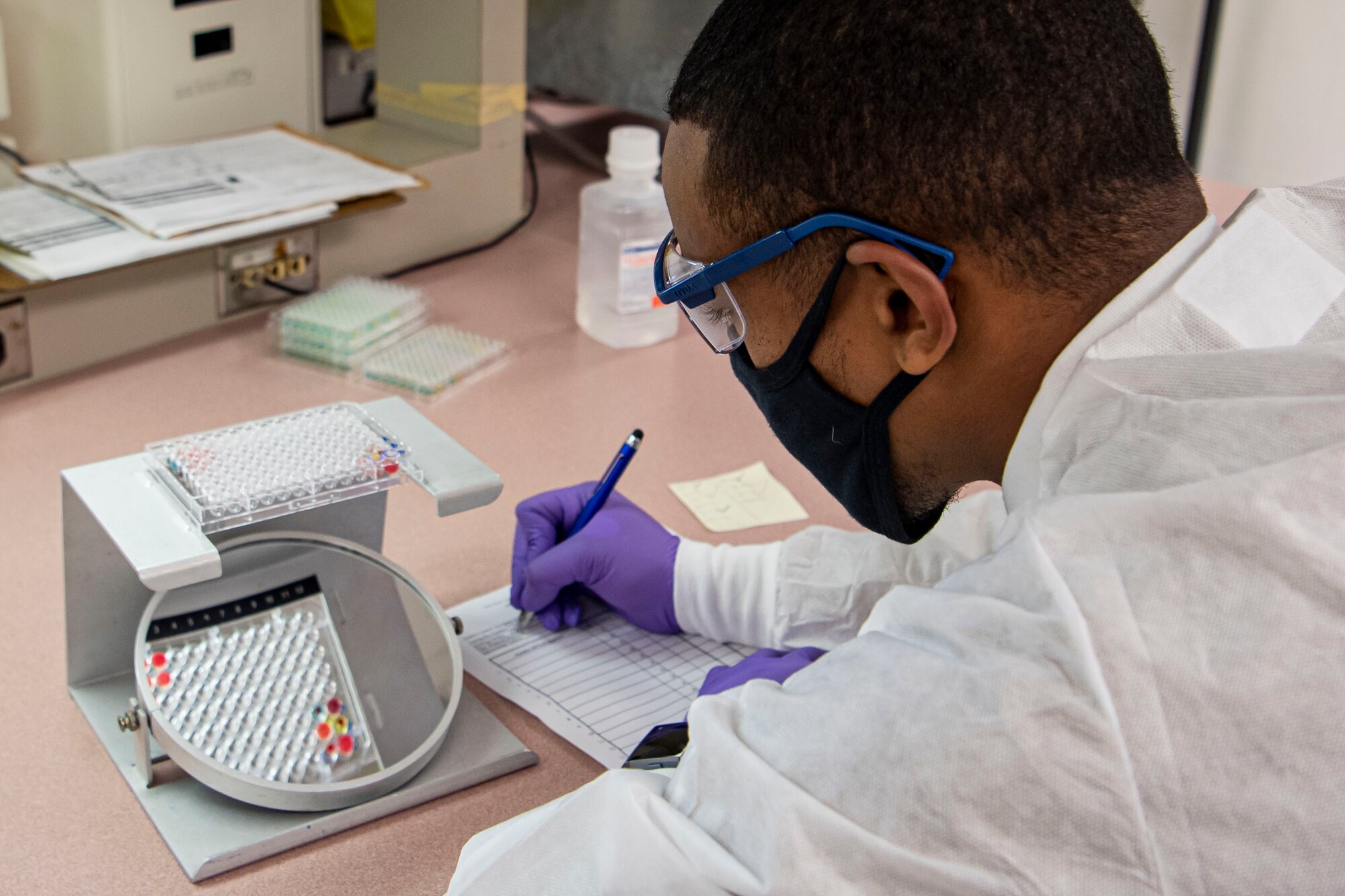 Photo of a sailor analyzes an assay plate.
