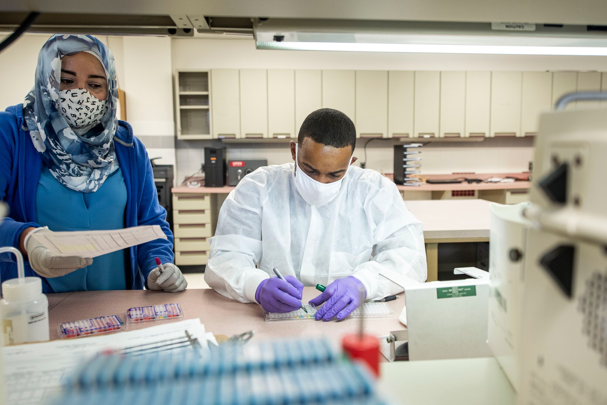 Photo of medical lab technicians preparing an assay plate.
