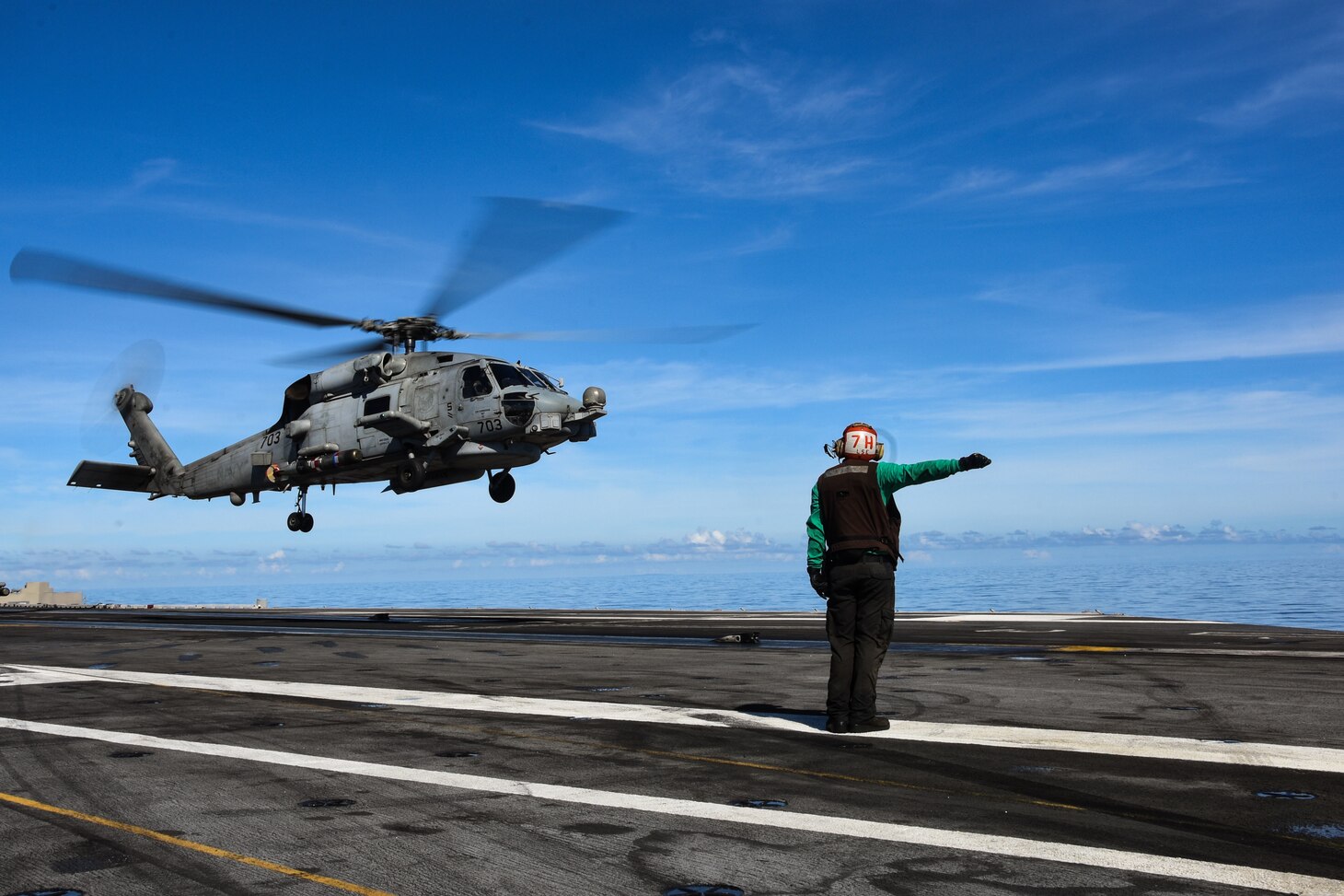 A Sailor signals to an MH-60R Sea Hawk prior to take off on the flight deck of the Navy�s only forward-deployed aircraft carrier USS Ronald Reagan (CVN 76) in support of Valiant Shield 2020.